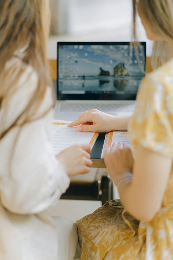 Two women working together on a laptop, focusing on documents. Perfect for themes of collaboration, teamwork, and technology.
